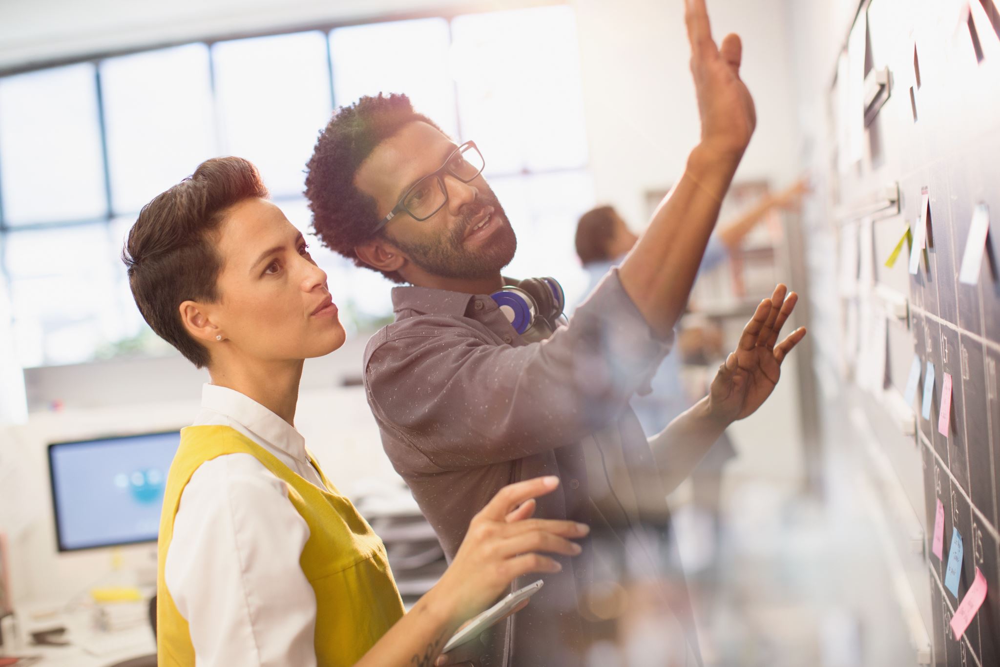 Two-colleagues-planning-on-board-with-sticky-notes